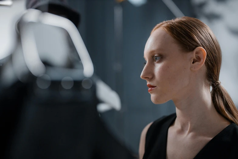 a woman in a black dress standing in front of a mirror, a character portrait, unsplash, hyperrealism, movie still of a cyborg, a redheaded young woman, westworld, cinestill colour