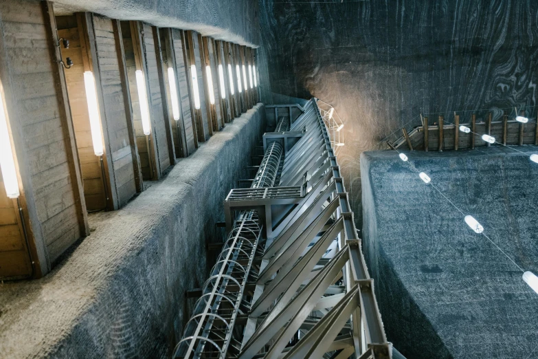 a room filled with lots of windows next to a wall, inspired by Filip Hodas, unsplash contest winner, brutalism, in dusty open pit mine, turbines, look down a cellar staircase, water reservoir