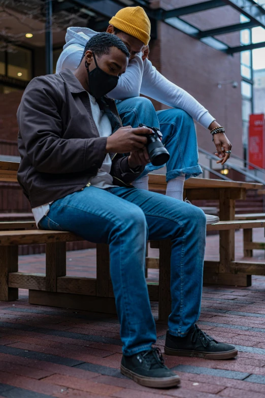 a couple of men sitting on top of a wooden bench, a picture, by Washington Allston, unsplash, visual art, jeans, shot with sony alpha 1 camera, full body profile camera shot, sneaker photo