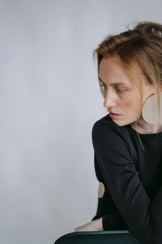 a woman sitting on a chair with her head in her hands, trending on pexels, bauhaus, 2 d lasercut earrings, white sleeves, standing, circle