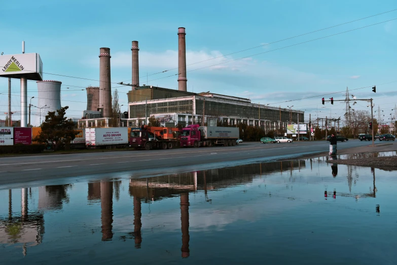 a train traveling down train tracks next to a puddle of water, by Carey Morris, photorealism, power plants, 2022 photograph, view from across the street, biroremediation plant