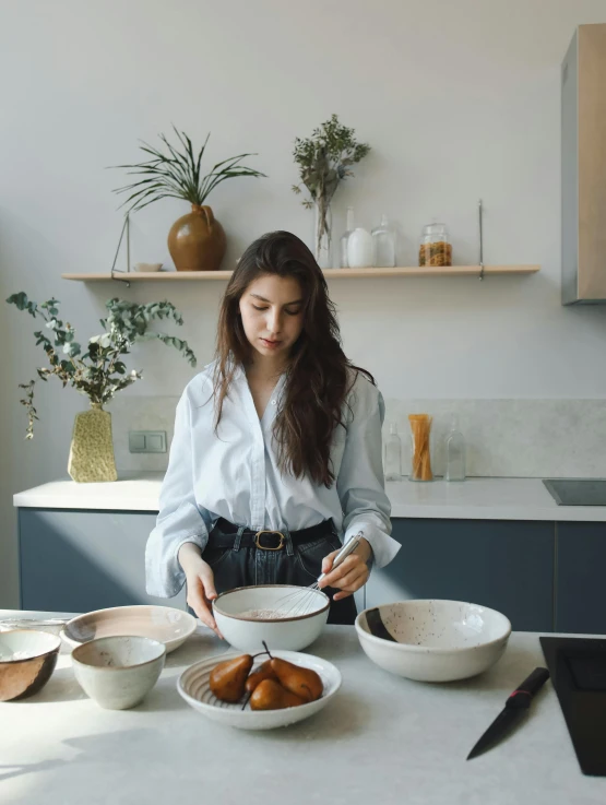 a woman standing in a kitchen preparing food, a portrait, by Alice Mason, pexels contest winner, handsome girl, white ceramic shapes, gif, low quality photo