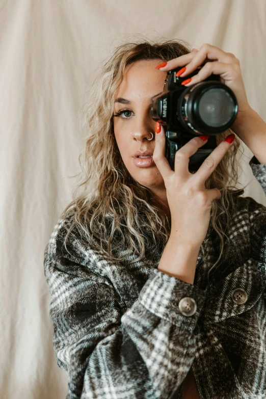 a woman taking a picture with a camera, trending on pexels, curly dirty blonde hair, looking seductive, gif, textured