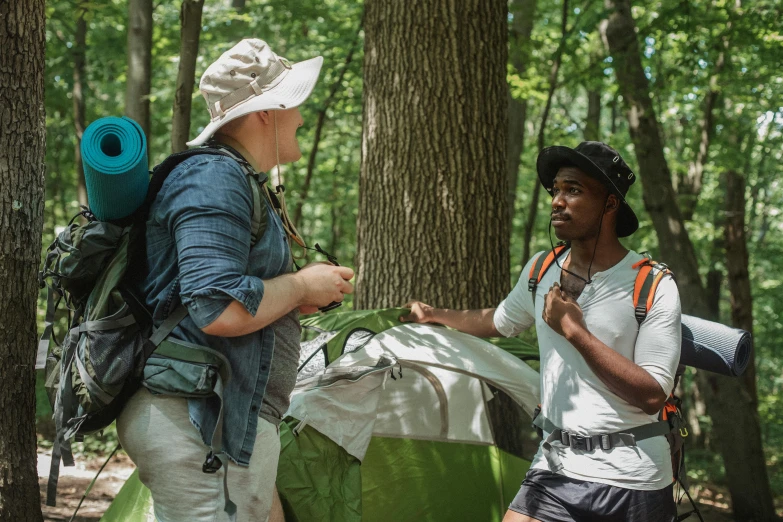 a couple of people that are standing in the woods, teaching, wearing adventure gear, shade, gray