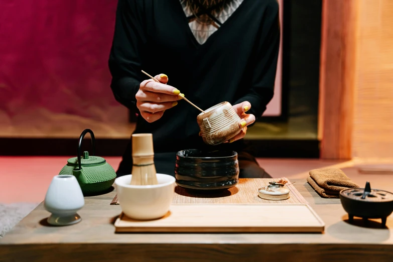 a man in a black shirt preparing food on a table, a still life, inspired by Kanō Shōsenin, trending on unsplash, ukiyo-e, wood cups, made of glazed, green tea, melbourne