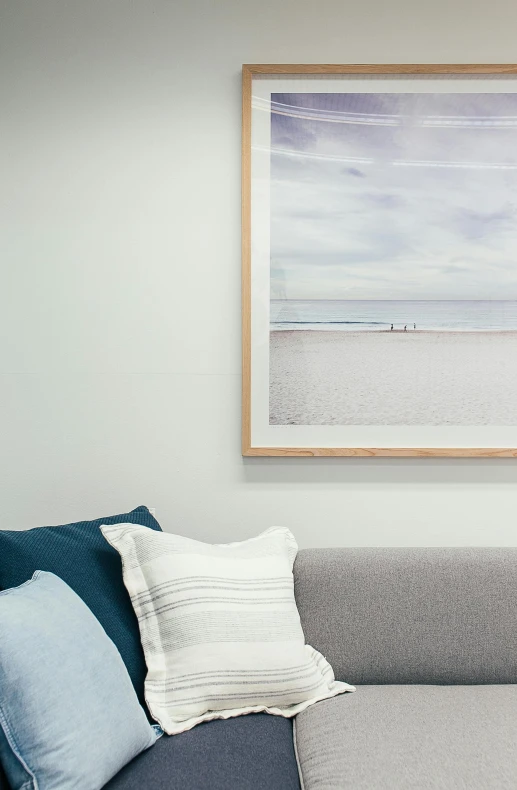 a living room with a couch and a picture on the wall, relaxing on the beach, zoomed in, colours, calming