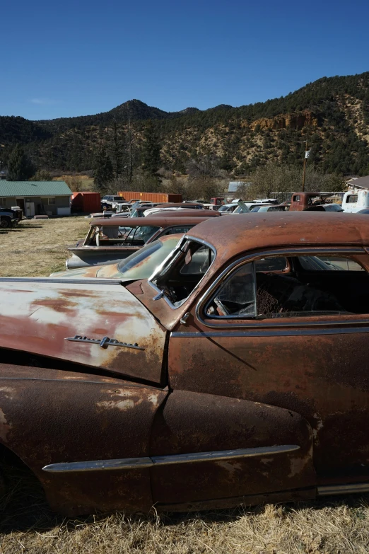 an old rusted car is parked in a field, unsplash, auto-destructive art, driving through a 1 9 5 0 s town, hillside, retro spaceships parked outside, square