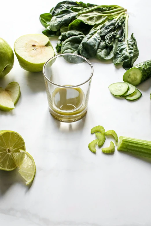 a table topped with fruits and vegetables next to a glass of juice, lime green, profile image, epicurious, apple