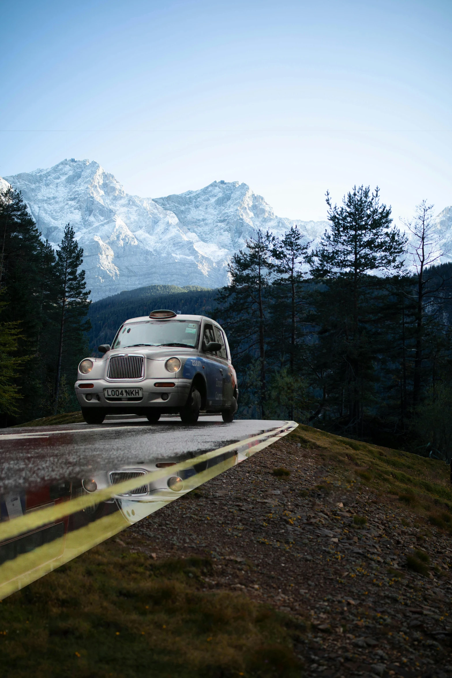 a car driving down a road with mountains in the background, taxis, moody iconic scene, square, alpine