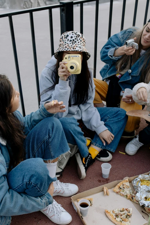 a group of women sitting on the ground eating pizza, a polaroid photo, inspired by Elsa Bleda, trending on pexels, graffiti, wearing double denim, wearing a yellow hoodie, teenage, hollywood promotional image