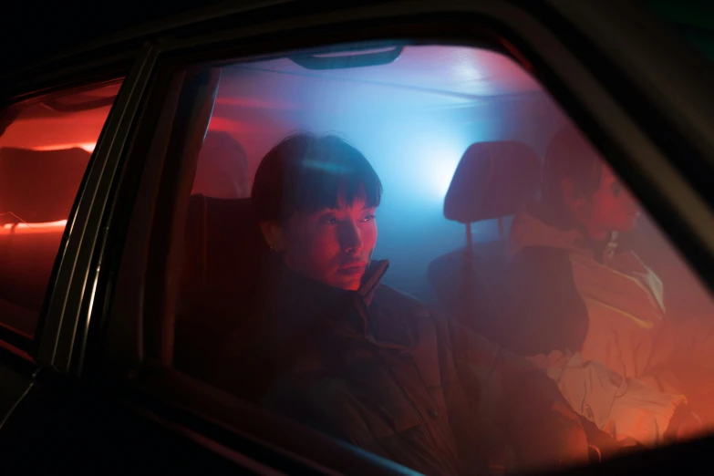 a man sitting in the passenger seat of a car, an album cover, by Adam Marczyński, pexels contest winner, conceptual art, police lights shine on her face, teenage boy, fog mads berg, still from stranger things