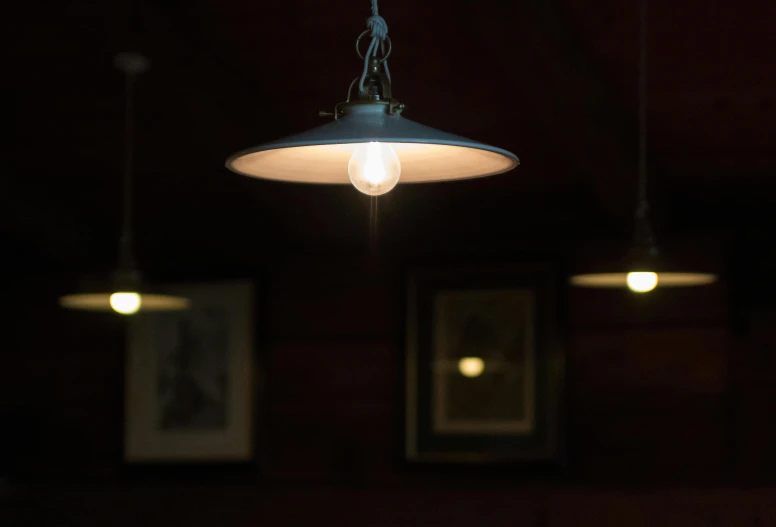 a couple of lights hanging from a ceiling, inspired by Brassaï, light inside the hut, edison bulb, in a medieval tavern at night, single light