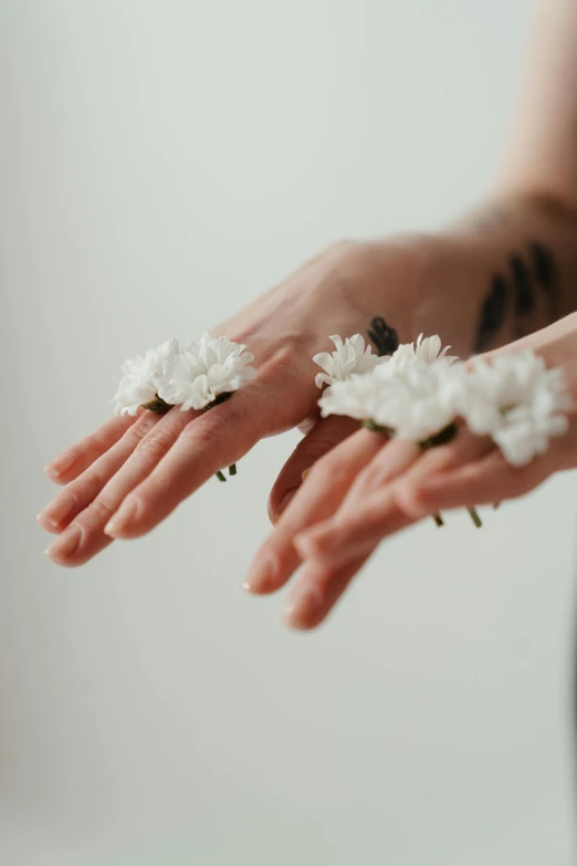 a woman holding two white flowers in her hands, a tattoo, inspired by Elsa Bleda, aestheticism, partially cupping her hands, connection rituals, zen aesthetic, 5 fingers