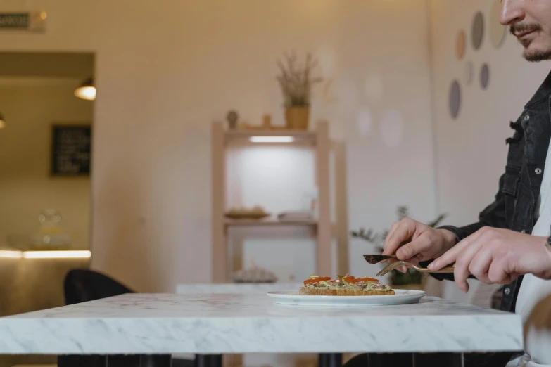 a man sitting at a table with a plate of food, pizza on a table, profile image, ignant, white marble interior photograph