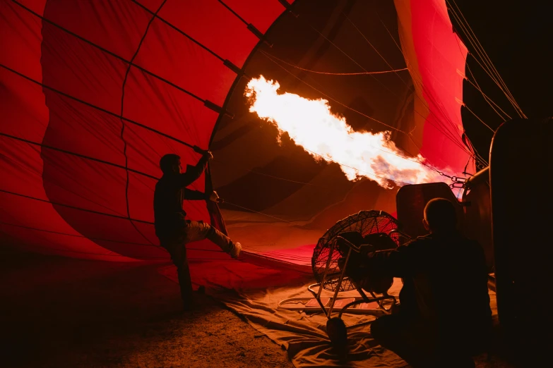 a couple of people that are inside of a hot air balloon, by Lee Loughridge, pexels contest winner, bathed in the the glow of a fire, red and cinematic lighting, lachlan bailey, behind the scenes photo