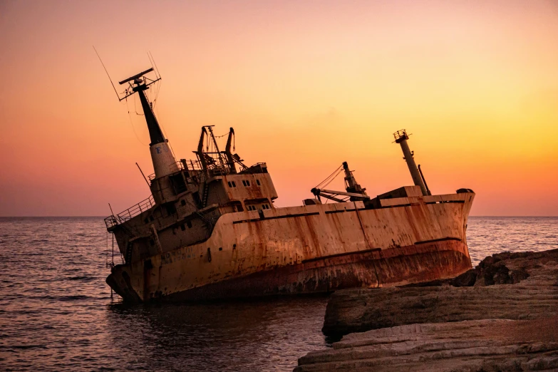 a rusted boat sitting on top of a body of water, an album cover, pexels contest winner, romanticism, pink golden hour, shipwrecks, cyprus, scientific photo