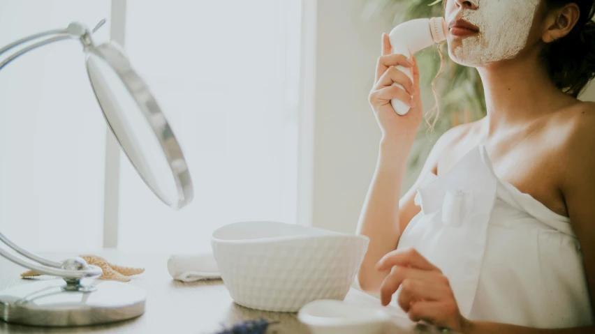 a woman sitting at a table with a facial mask on, pexels contest winner, wearing white robe, manuka, with a mirror, profile image