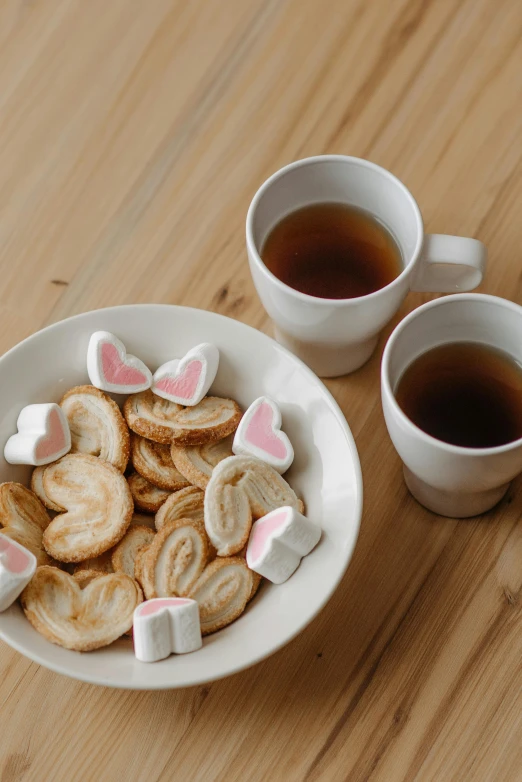a plate of cookies and cups of tea on a table, by Tan Ting-pho, pexels contest winner, dau-al-set, bunnies, adult pair of twins, hearts, medium closeup