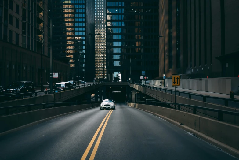 a car driving down a street next to tall buildings, by Andrew Domachowski, pexels contest winner, chicago, tunnels, unsplash 4k, multiple stories