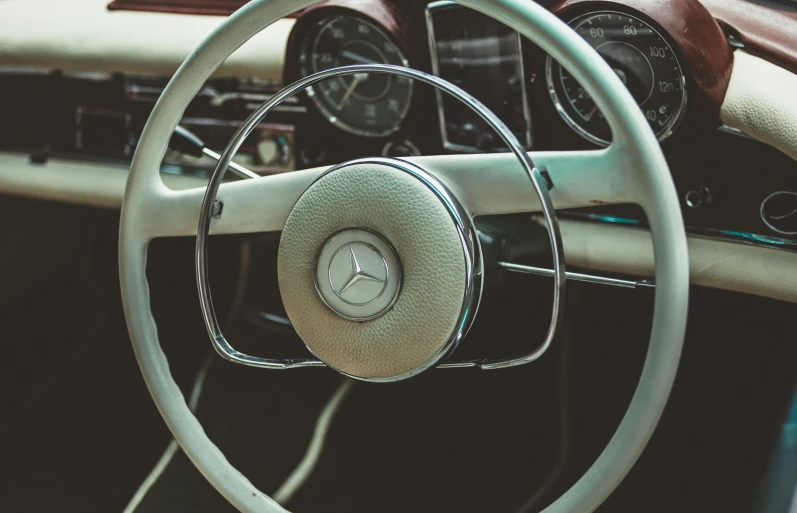 a close up of a steering wheel in a car, an album cover, trending on pexels, retrofuturism, mercedez benz, dressed in a worn, unsplash contest winning photo, quiet beauty