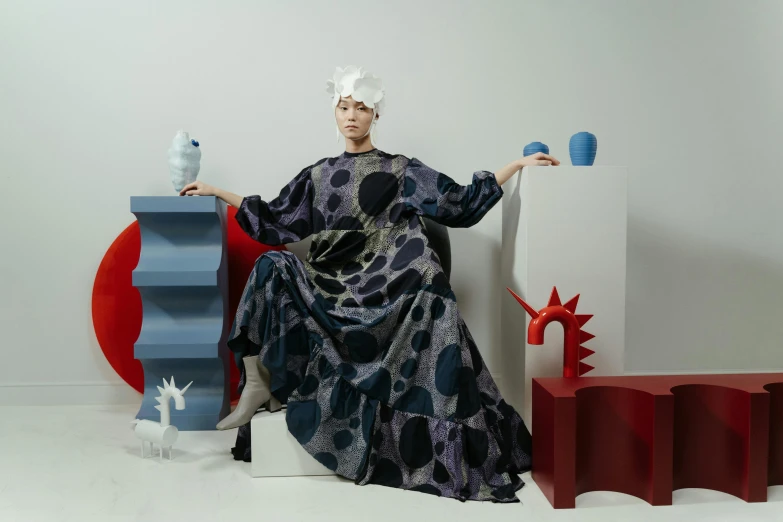 a woman sitting on a chair in a room, inspired by Gao Cen, maximalism, voluminous sleeves, wearing long gown, press shot, polka dot