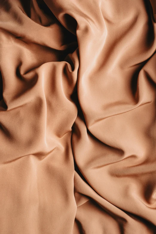 a brown cloth is laying on top of a bed, trending on pexels, flowing salmon-colored silk, tan complexion, insanely details, dark hues