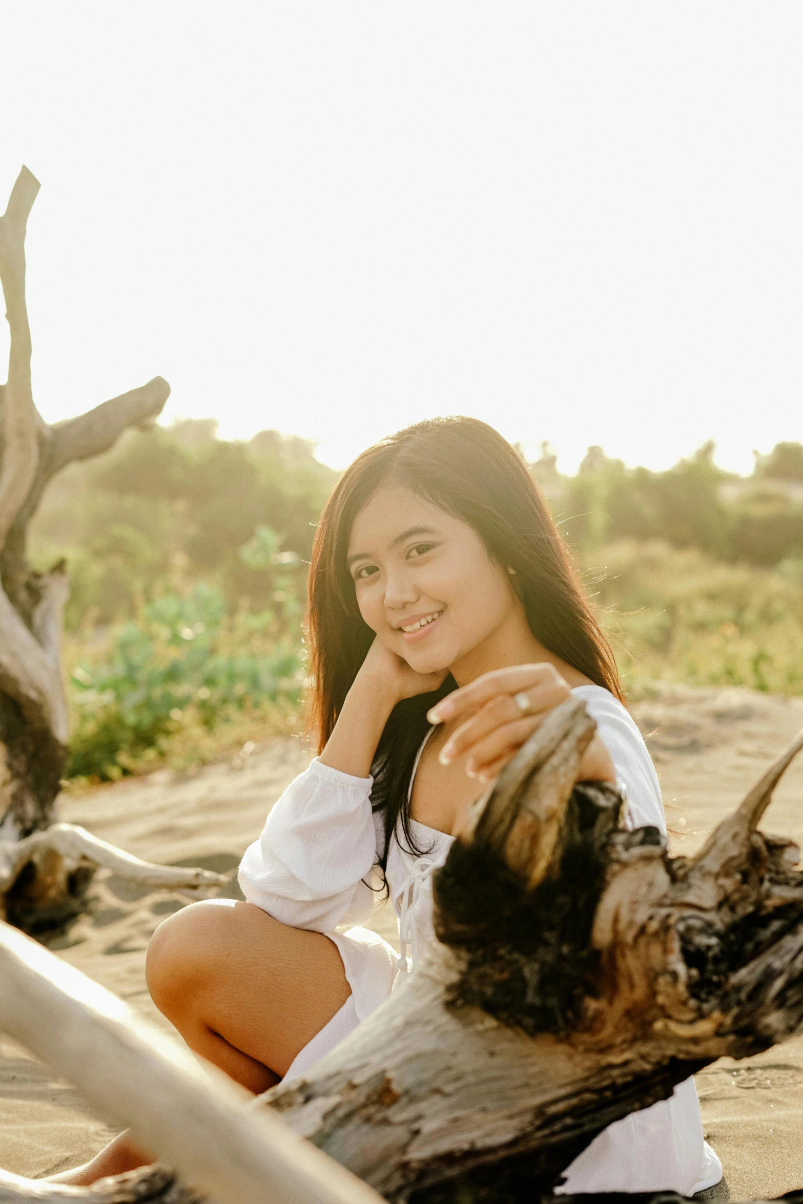 a woman sitting on top of a beach next to a tree, charming smile, portrait of modern darna, profile image, morning glow