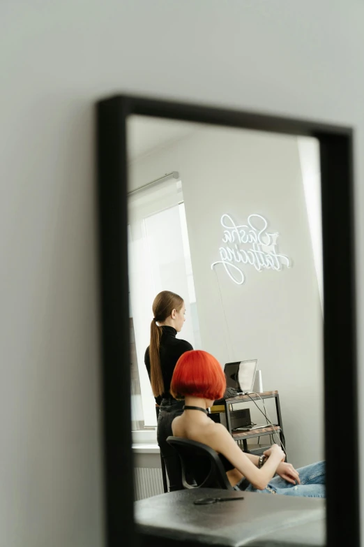 a woman sitting in a chair in front of a mirror, poster art, trending on pexels, black and red hair, bright signage, tattoo parlor photo, light box