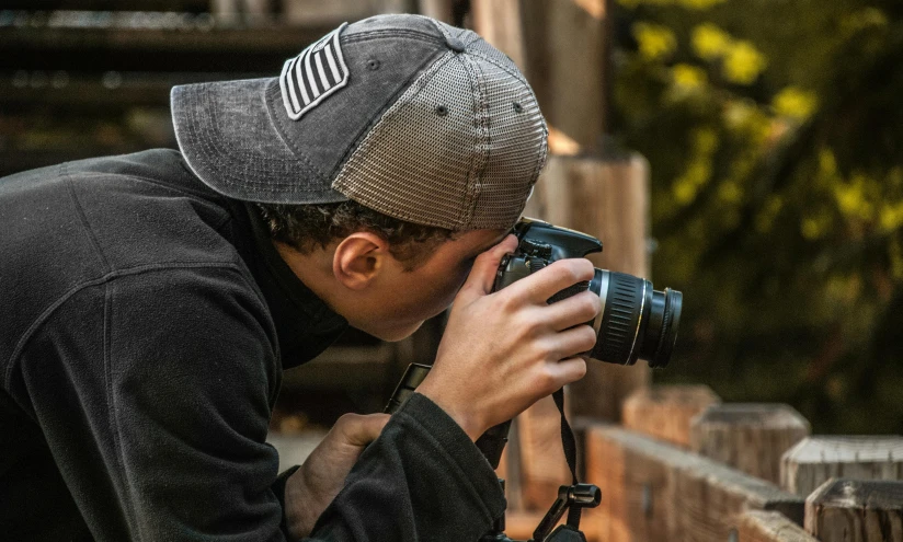 a man taking a picture of a giraffe with a camera, by Neil Blevins, pexels contest winner, photorealism, wearing a backwards baseball cap, headshot profile picture, covered with tar. dslr, in an action pose