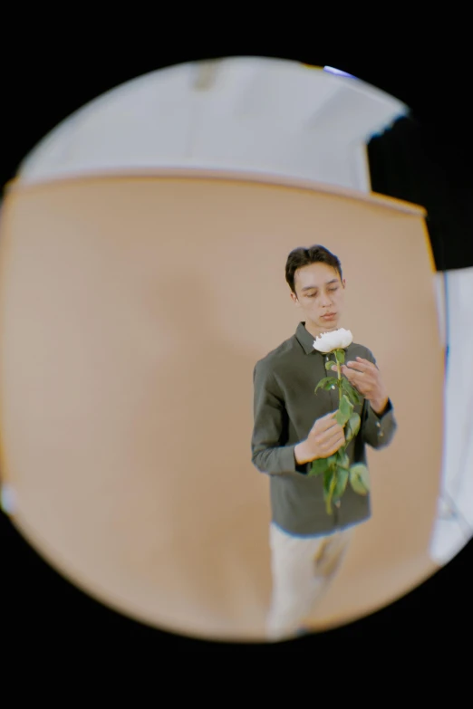 a man standing in front of a mirror holding a flower, inspired by Russell Dongjun Lu, trending on pexels, photorealism, melanchonic rose soft light, editorial footage, taken with sony alpha 9, a high angle shot