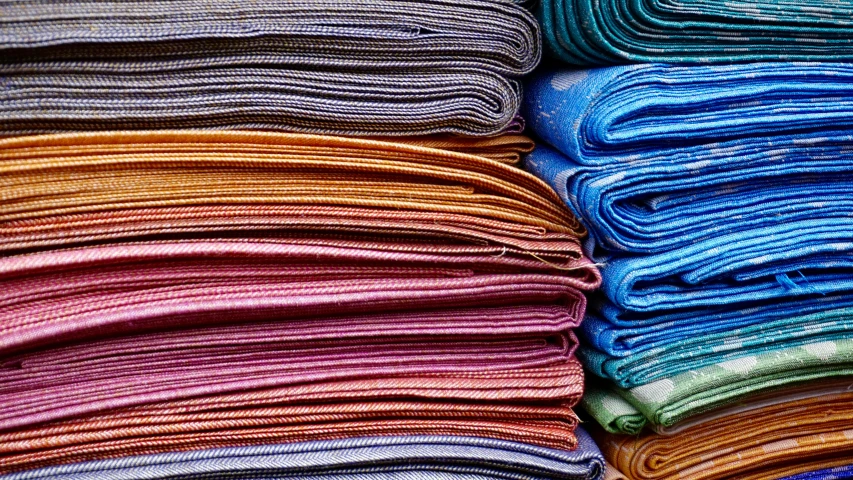 a pile of folded towels sitting on top of each other, by Carey Morris, unsplash, color field, several layers of fabric, silk tarps hanging, thumbnail, intricate colors