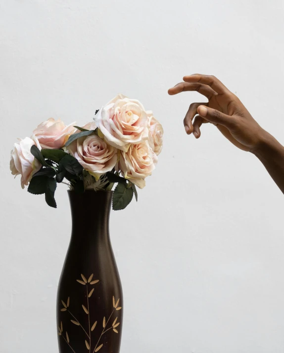 a person reaching for a flower in a vase, inspired by Robert Mapplethorpe, crown of peach roses, press shot, brown and cream color scheme, detailed product shot