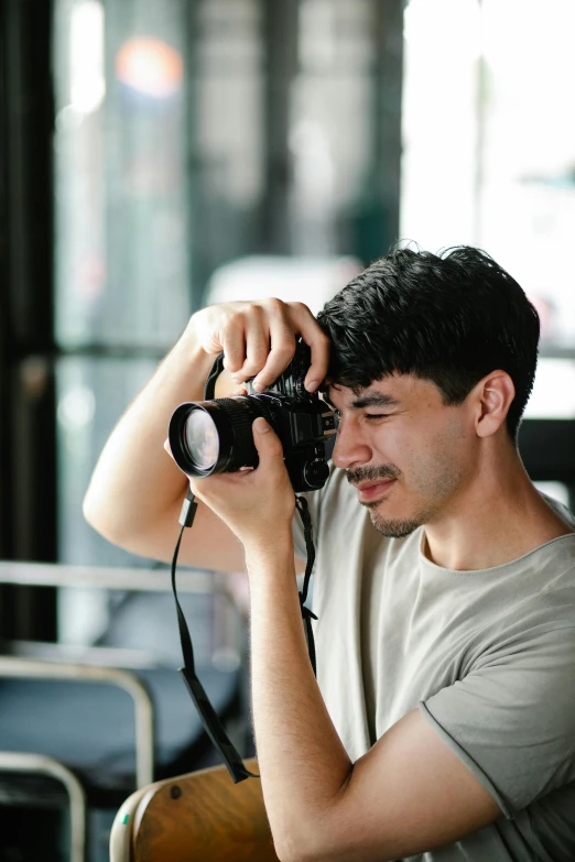 a man taking a picture with a camera, looking to the side off camera, sneering at the camera, body and headshot, over-the-shoulder shot