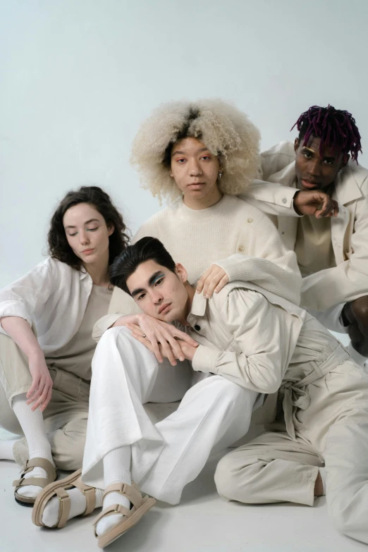 a group of people sitting next to each other, an album cover, inspired by Louis Le Nain, an all white human, non binary model, wearing a track suit, linen