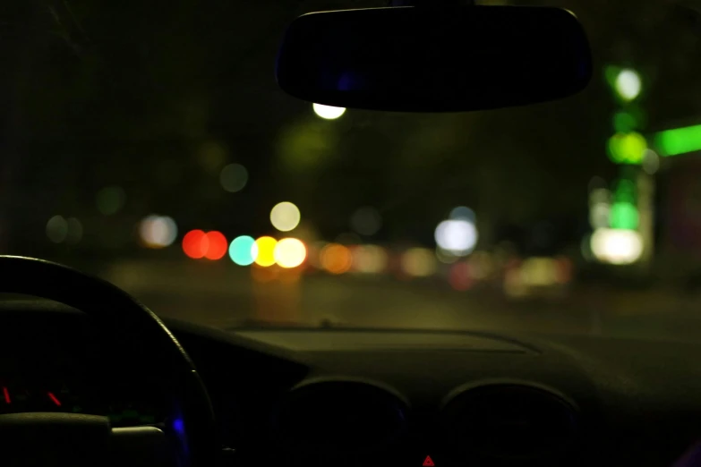 a car driving down a city street at night, out of focus, looking outside, looking across the shoulder, close-up photograph