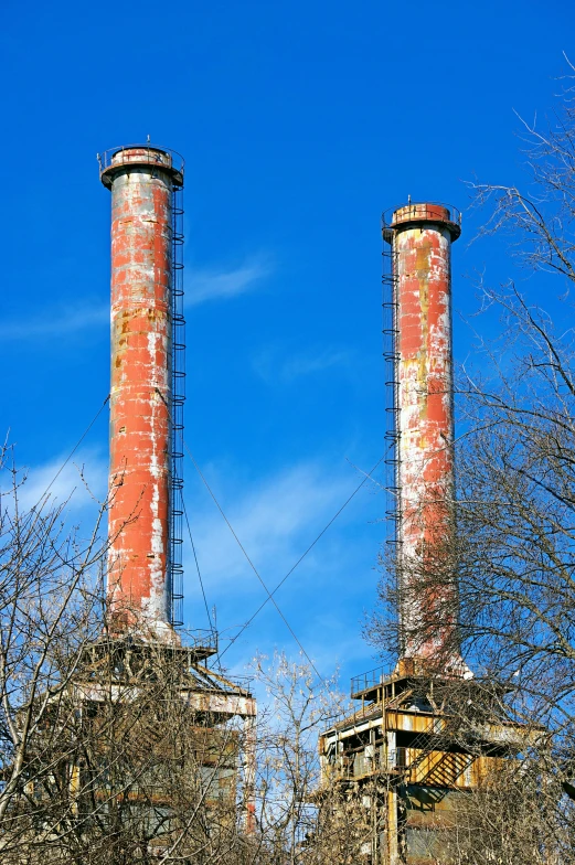 a couple of pipes sticking out of the side of a building, high towers, chimneys, abandoned structures, blue skies