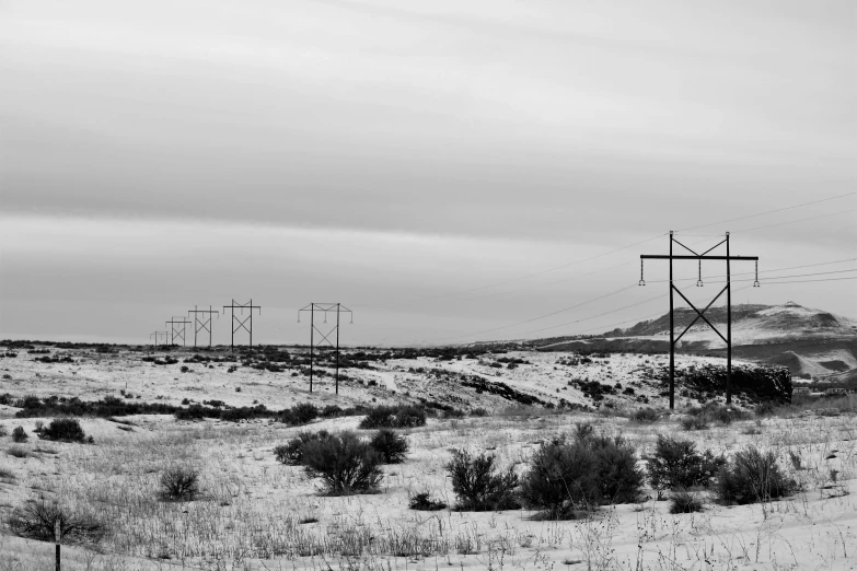 a black and white photo of power lines in the snow, by Jeffrey Smith, unsplash, new mexico desert, landscape of flat wastelands, fineartamerica, fields