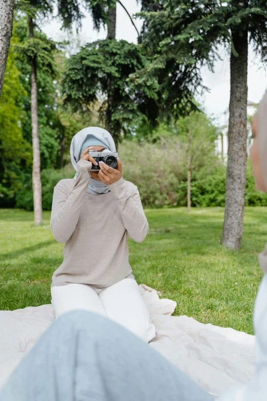 a woman taking a picture of herself with a camera, by Basuki Abdullah, having a picnic, white hijab, calmly conversing 8k, medium format