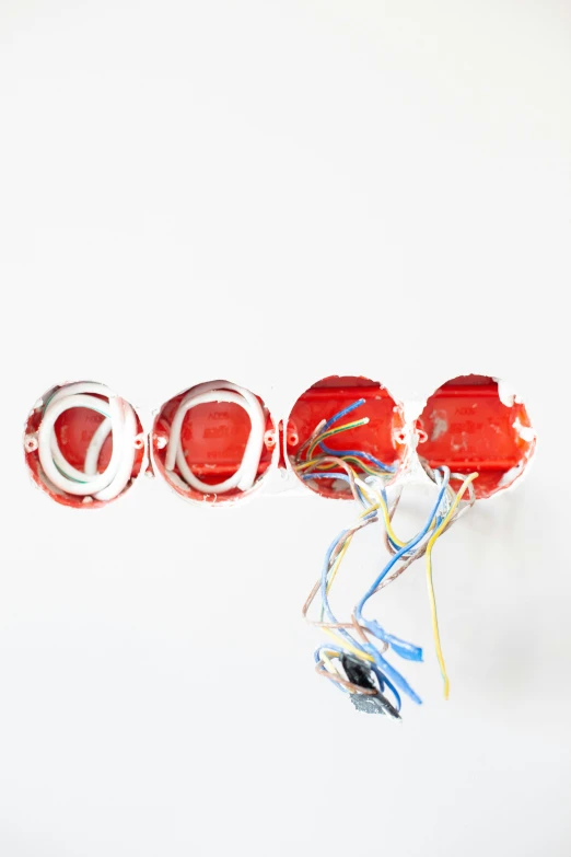 a group of red and white lollipops sitting on top of each other, inspired by Cerith Wyn Evans, with sparking circuits, fire, set against a white background, wiring