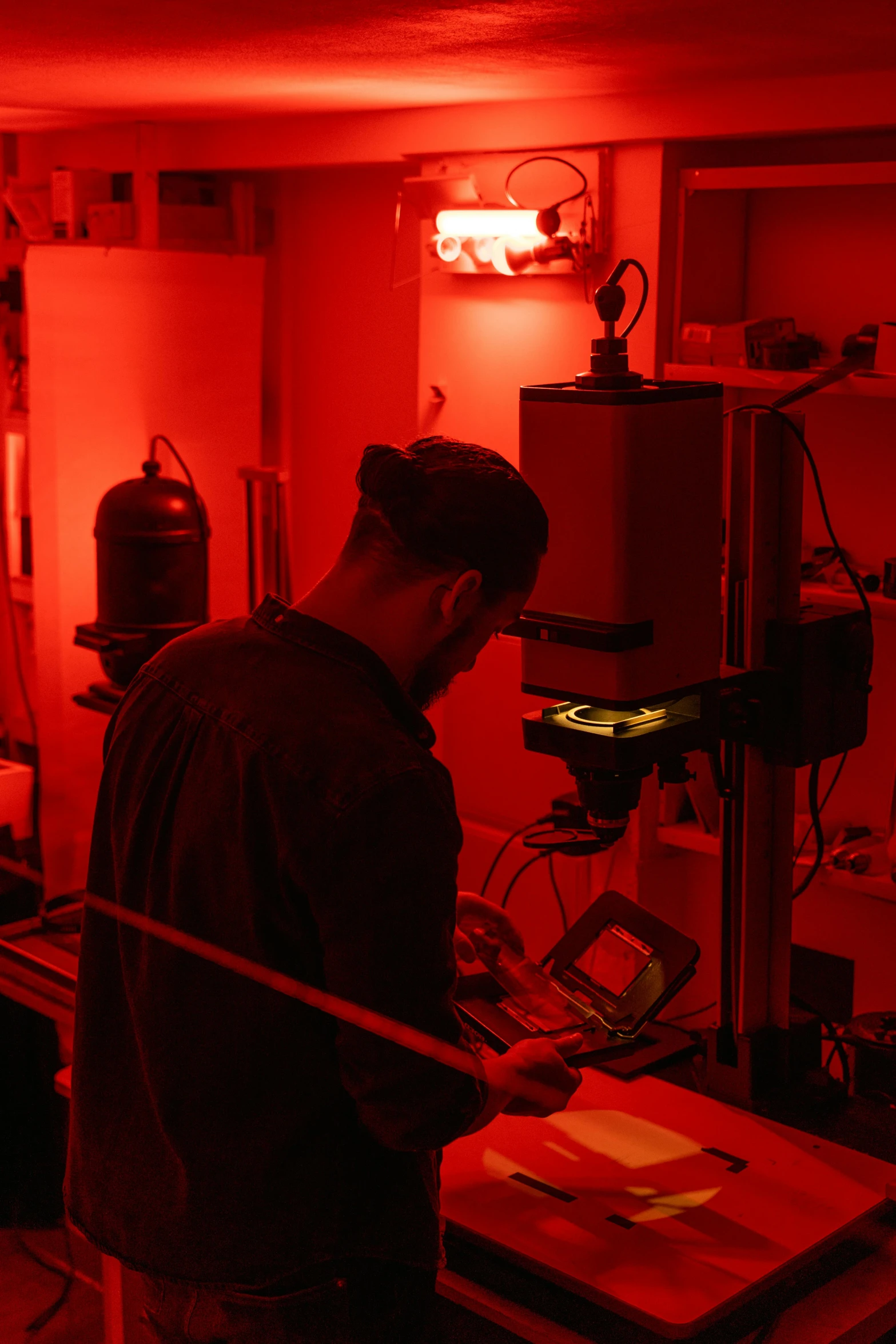 a man standing in a room with a red light, scientific equipment, working, contemplating, bottom lighting