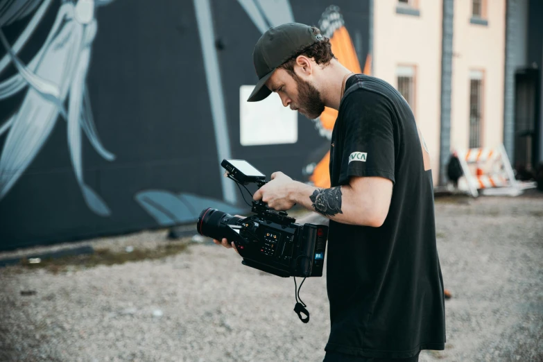 a man standing in front of a building holding a camera, graffiti, production ig, 8 k movie still, action sports, filmstill