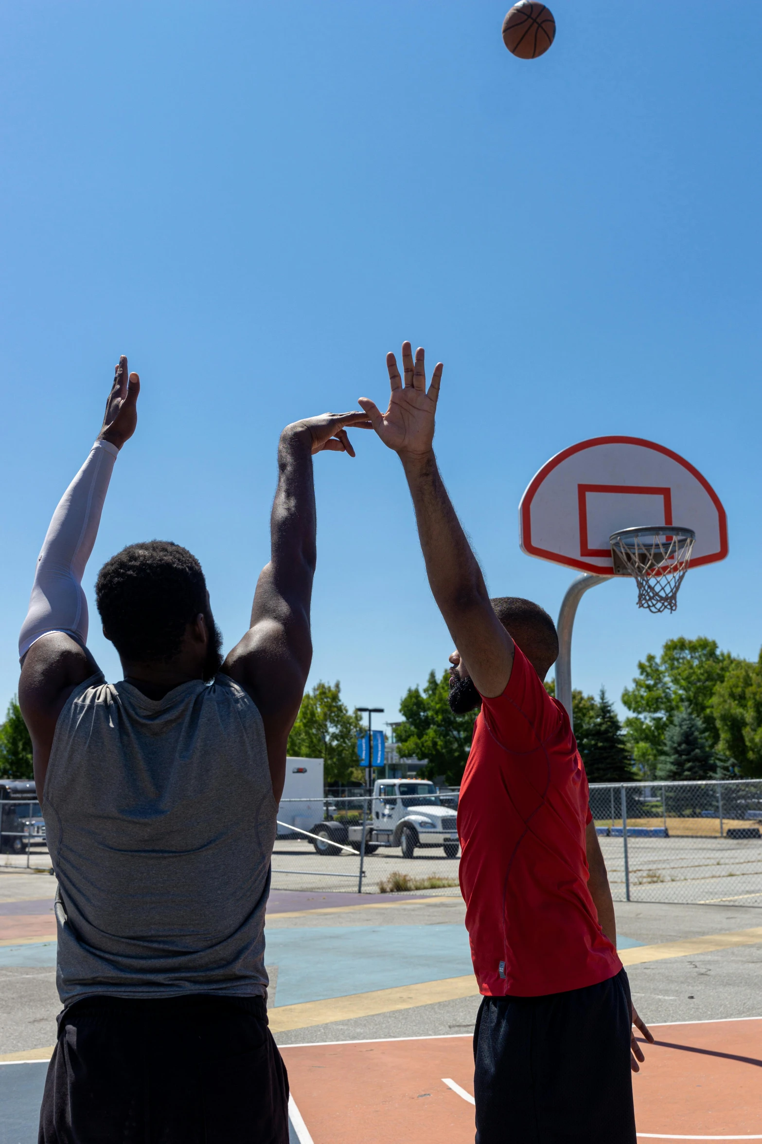 a couple of men standing on top of a basketball court, by Washington Allston, unsplash, hands in the air, square, cel - shaded, outside in parking lot