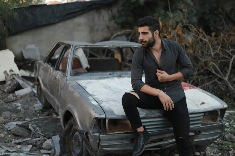 a man sitting on the hood of a car, by Ismail Acar, pexels contest winner, auto-destructive art, wearing elegant casual clothes, assyrian, mid-shot of a hunky, dressed in a gray