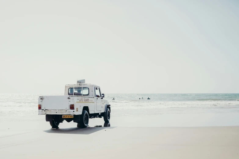 a white truck parked on top of a sandy beach, pexels contest winner, minimalism, back facing, mechanic, sea foam, an olive skinned