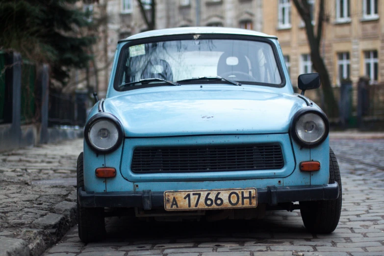 a small blue car parked on a cobblestone street, unsplash, socialist realism, square, ukraine. professional photo, 000 — википедия, faded worn