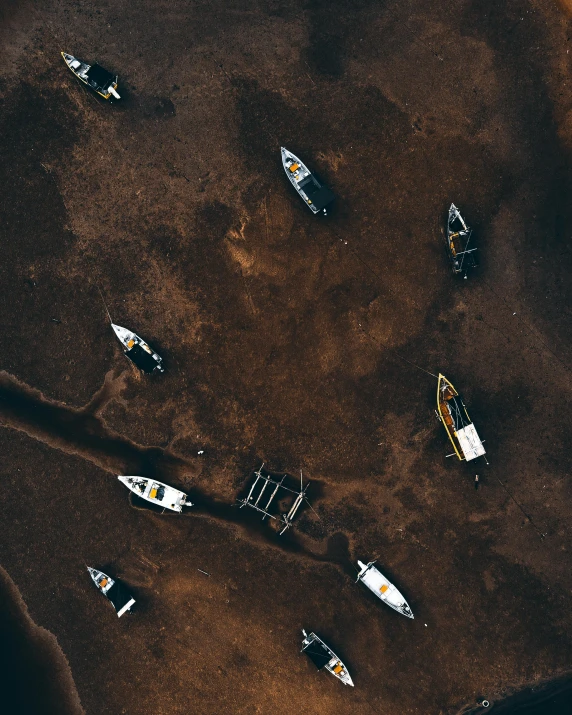 a group of boats sitting on top of a sandy beach, a screenshot, by Adam Marczyński, pexels contest winner, sea floor, plane, brown mud, dark. no text