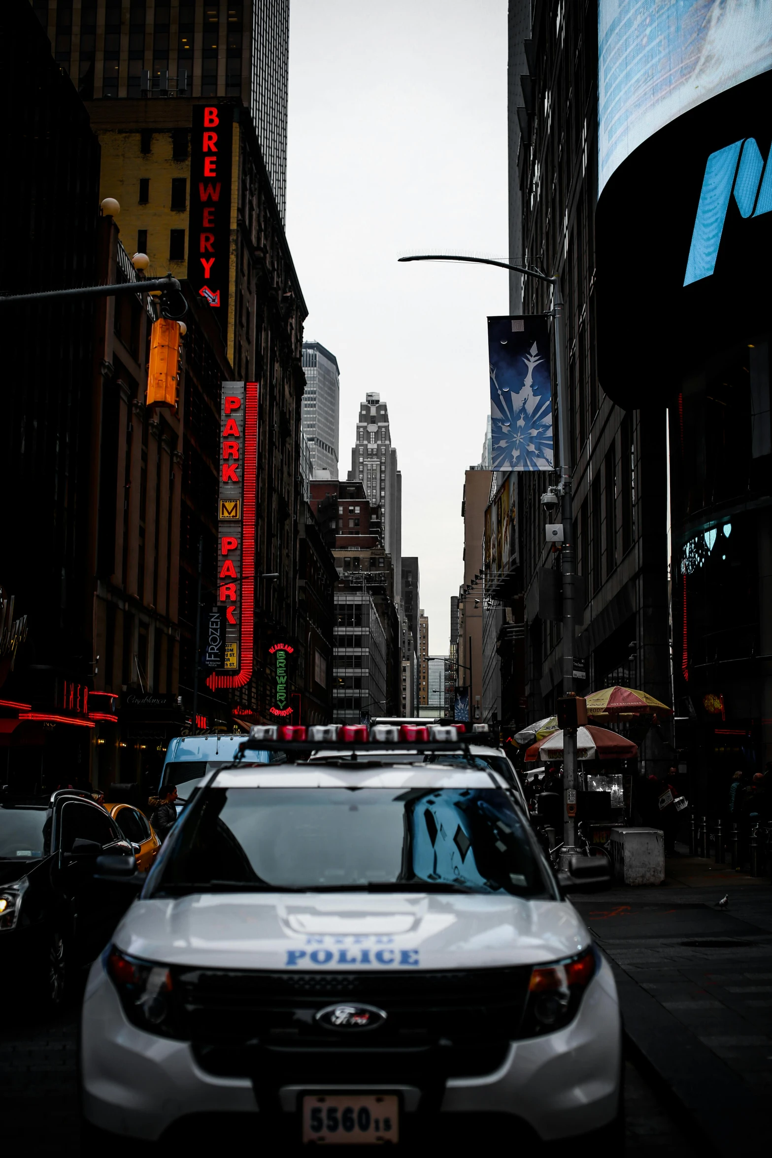 a police car driving down a city street, by Chris Rallis, pexels, new york times, stacked image, multiple stories, ominous photo