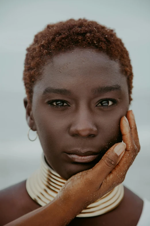 a close up of a person holding a cell phone, afrofuturism, defined cheekbones, curly copper colored hair, in africa, photo of a woman