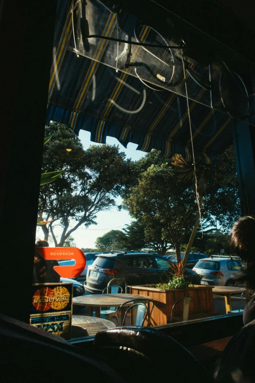 a man sitting at a table in front of a window, viewed through the cars window, kahikatea, comfy ambience, oceanside