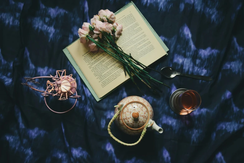 an open book sitting on top of a table next to a cup of tea, a still life, pexels contest winner, romanticism, blue and pink accents, copper and deep teal mood, bed of flowers on floor, connection rituals